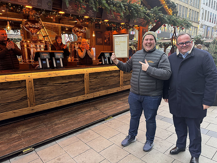 Prämiert als schönster Stand 2024: Sebastian Willenborg vomm Willenborgs Crambambuli auf dem Münchner Christkindlmarkt erhielt eine Urkunde von Wirtschaftsreferent Clemens Baumgärtner 